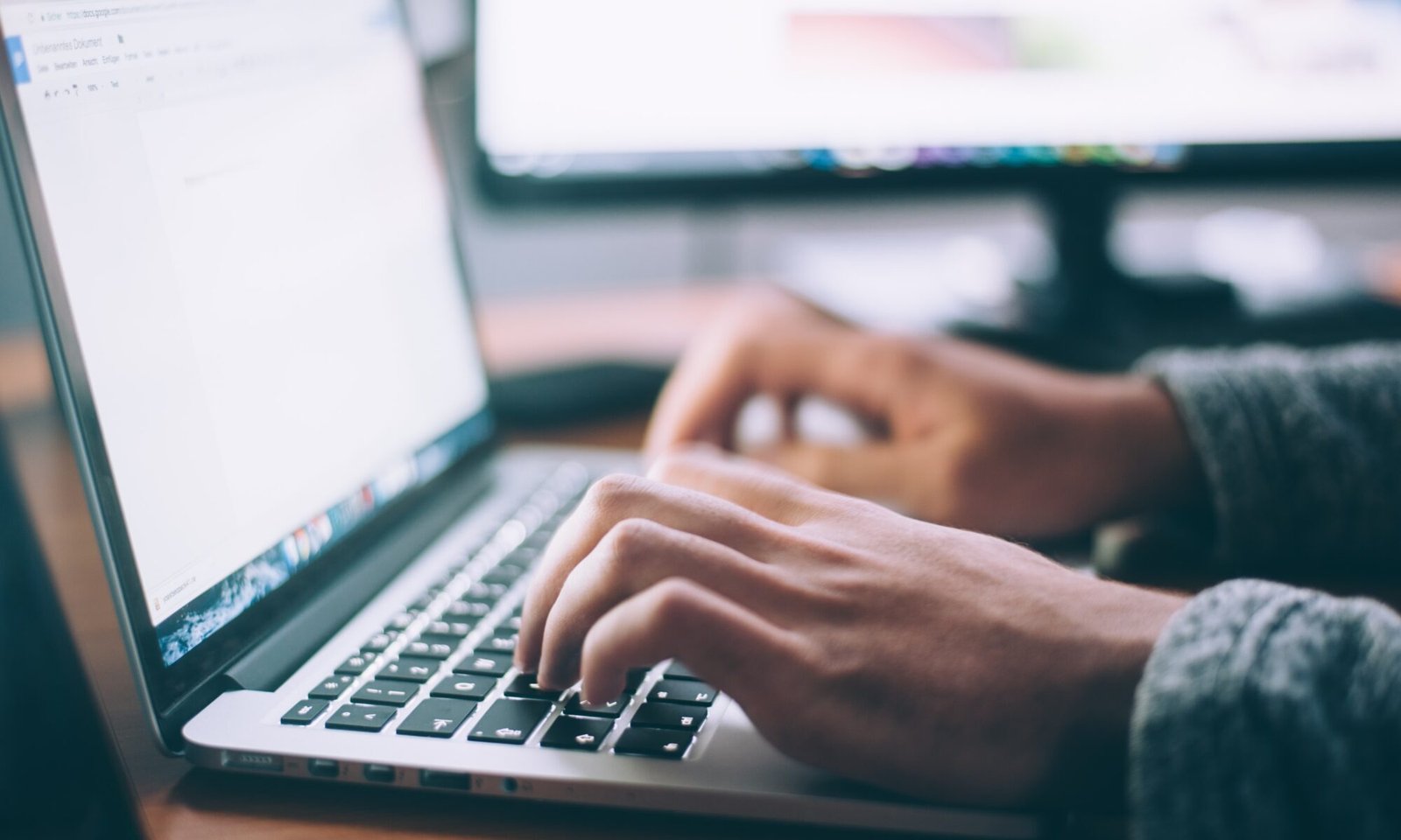 Pessoa mexendo em um notebook com o foco em suas mãos