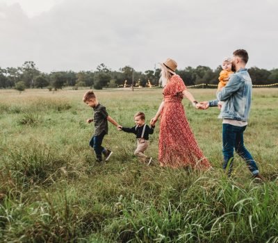 Família caminhando de mãoes dadas por campo verde